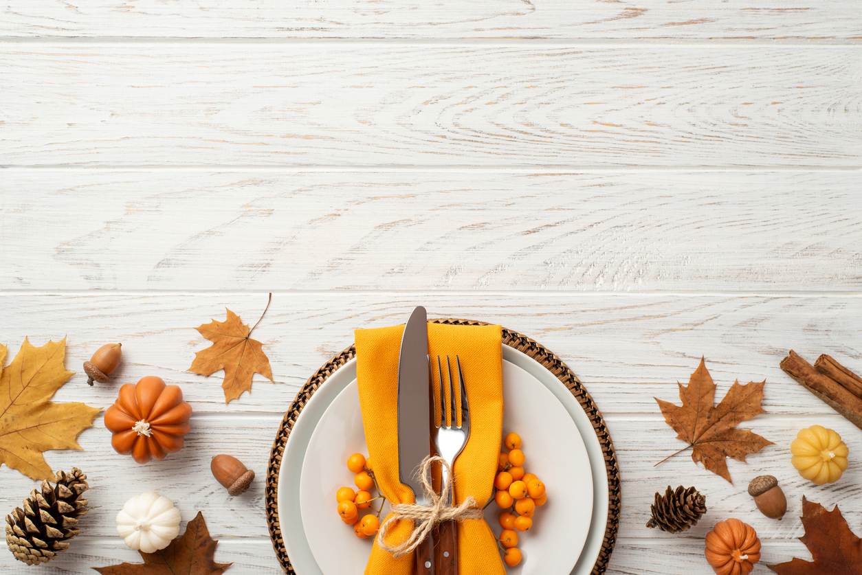 A dinner plate is set with a knife, fork, and napkin, while surrounded by acorns, leaves, and pine cones.