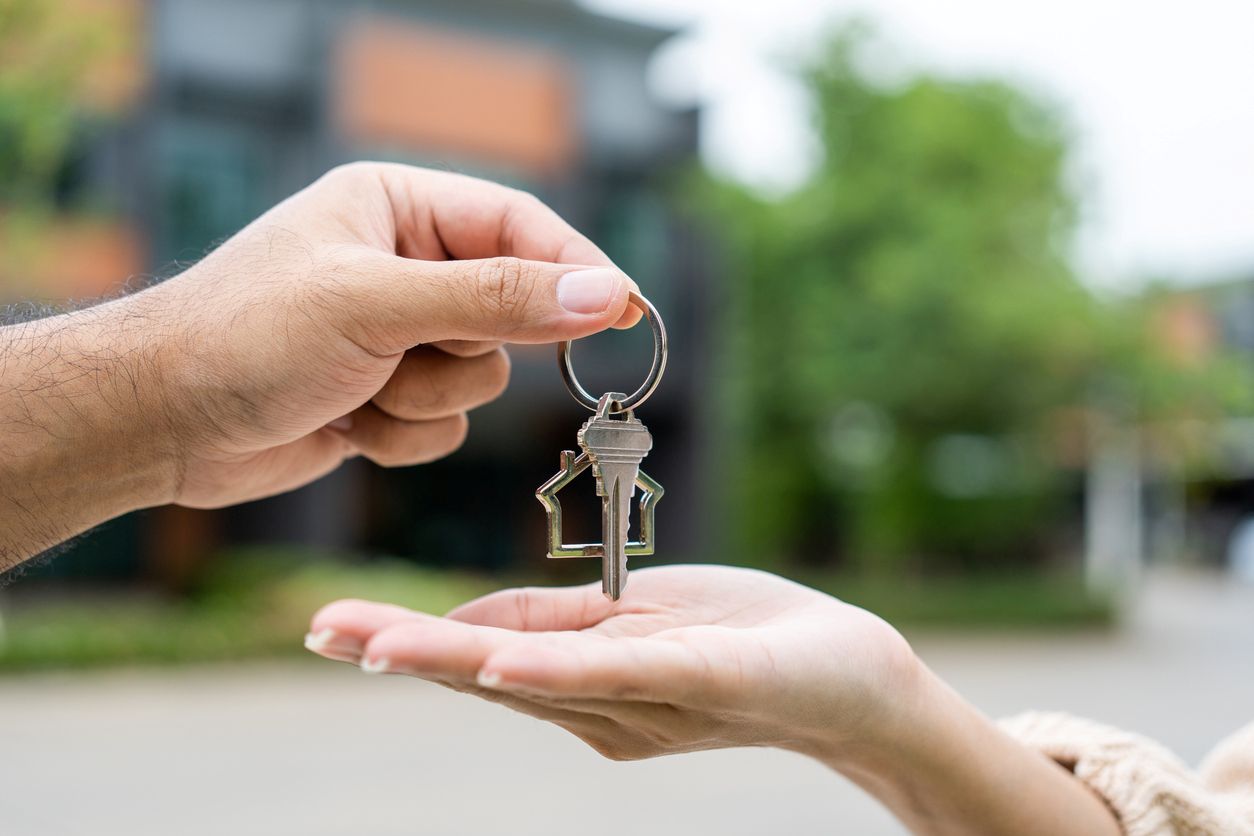 A woman receiving the keys to her new home, and the keys have a house keychain.