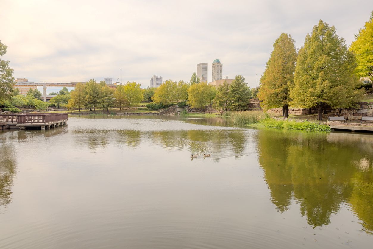 A park with a lake surrounded by trees in Tulsa, OK.