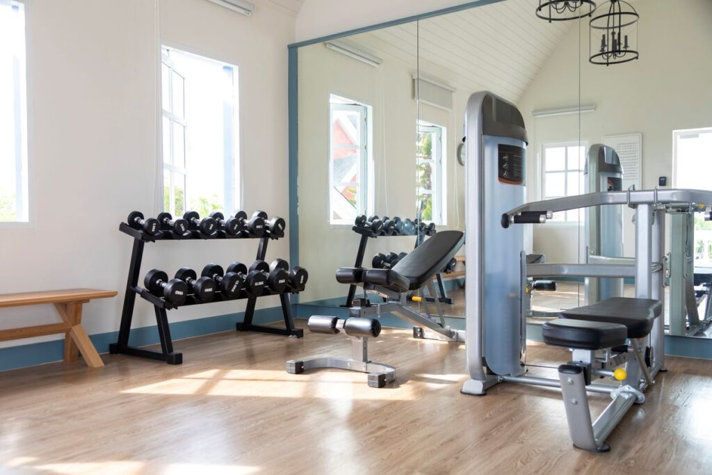 An apartment community gym featuring racks of dumbbells, weight machines, and a workout bench.